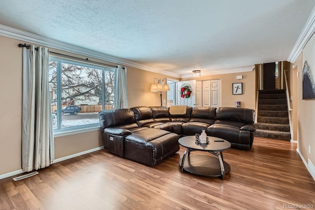 living room with hardwood / wood-style flooring, ornamental molding, and a textured ceiling