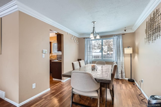 dining area with a textured ceiling, crown molding, and hardwood / wood-style floors