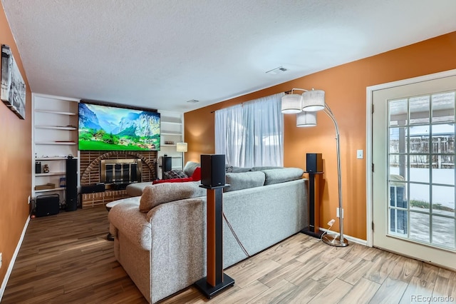 living room featuring a wealth of natural light, a brick fireplace, hardwood / wood-style floors, and a textured ceiling