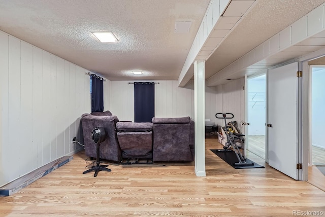 living room featuring a textured ceiling, wood walls, and light hardwood / wood-style flooring