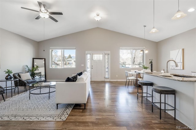 living area featuring baseboards, lofted ceiling, dark wood-style floors, and a ceiling fan