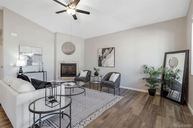 living area with wood finished floors, a fireplace, baseboards, and lofted ceiling