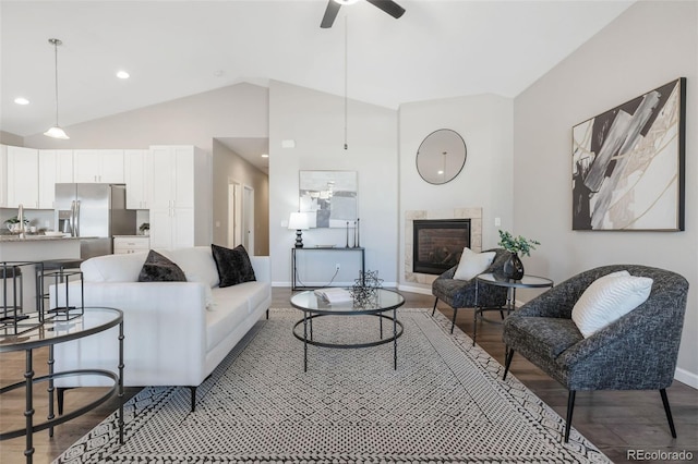 living area with lofted ceiling, a ceiling fan, wood finished floors, baseboards, and a tile fireplace