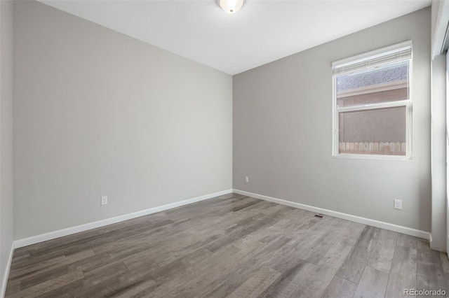 unfurnished room with baseboards and wood finished floors