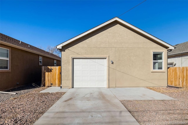 exterior space with stucco siding, a garage, driveway, and fence