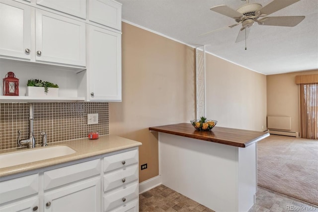 kitchen featuring baseboard heating, white cabinetry, and sink