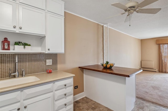 690 S Alton Way Unit 1C, Denver, CO 80247 - kitchen featuring a sink, a baseboard radiator, a ceiling fan, backsplash, and white cabinetry