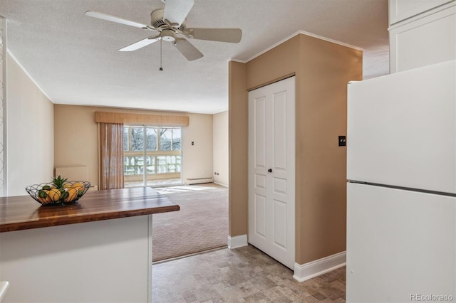 kitchen with white fridge, wooden counters, and a textured ceiling