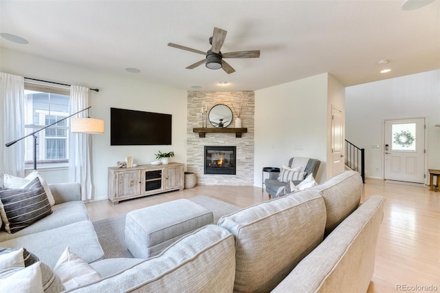 15389 W 50th Dr, Golden, CO 80403 - living room featuring ceiling fan, light wood-style floors, stairs, a stone fireplace, and baseboards