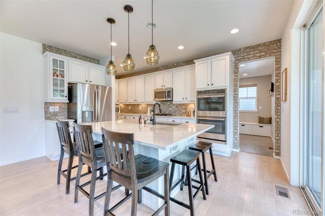 15389 W 50th Dr, Golden, CO 80403 - kitchen featuring stainless steel appliances, light wood-type flooring, a breakfast bar area, white cabinets, and recessed lighting