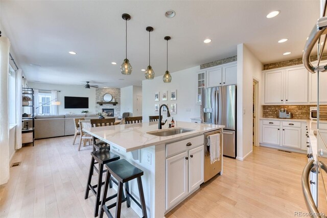 15389 W 50th Dr, Golden, CO 80403 - kitchen with a sink, stainless steel appliances, a stone fireplace, light stone counters, and a ceiling fan