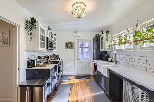 kitchen featuring sink, dark hardwood / wood-style floors, backsplash, white cabinets, and appliances with stainless steel finishes