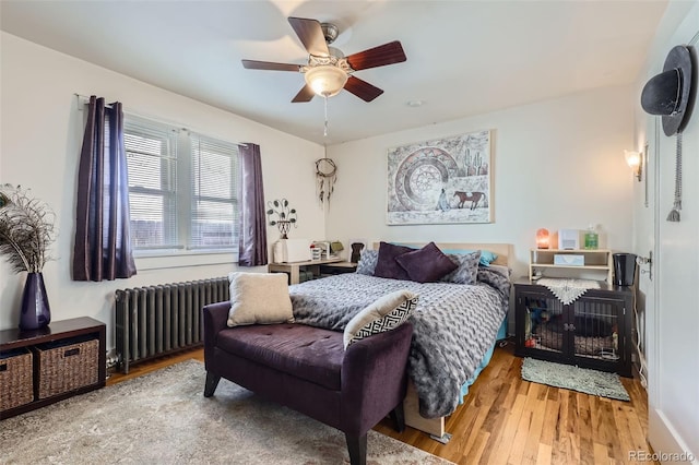 bedroom featuring ceiling fan, radiator heating unit, and wood-type flooring