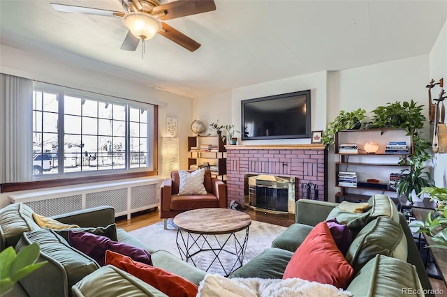 living room featuring hardwood / wood-style flooring, ceiling fan, a fireplace, and radiator