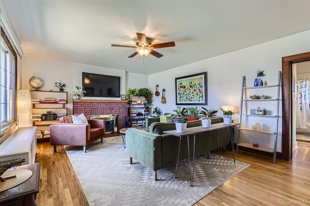 living room with a fireplace, light hardwood / wood-style floors, and ceiling fan