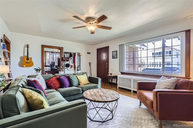 living room featuring radiator heating unit, light wood-type flooring, and ceiling fan