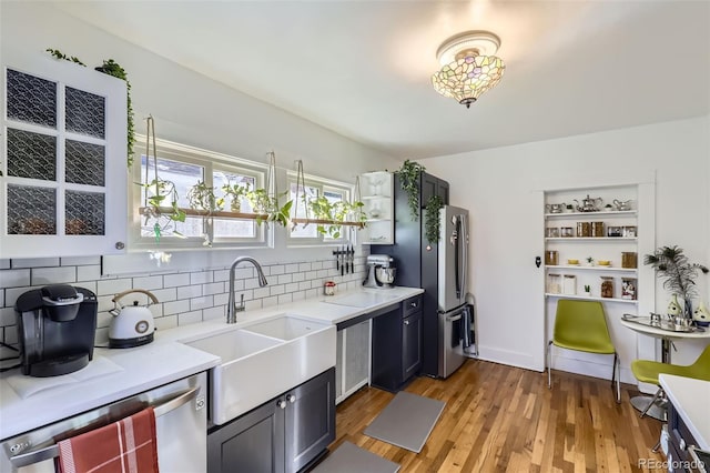 kitchen featuring backsplash, stainless steel appliances, sink, and light hardwood / wood-style flooring