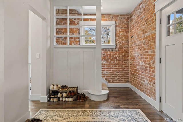 doorway featuring dark wood-type flooring and brick wall