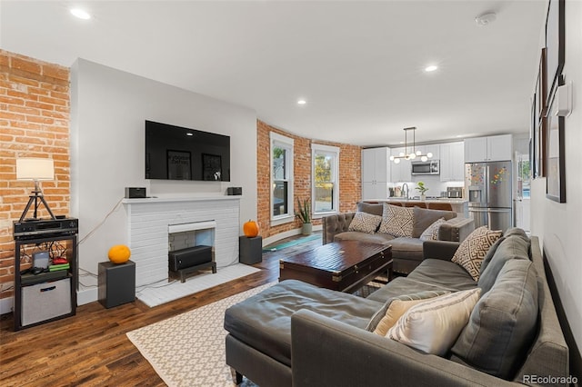 living room featuring hardwood / wood-style flooring, a fireplace, a chandelier, and sink