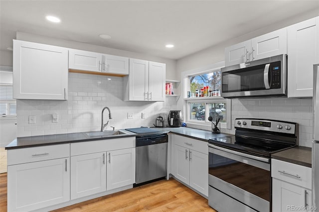 kitchen featuring stainless steel appliances, sink, white cabinets, and light wood-type flooring