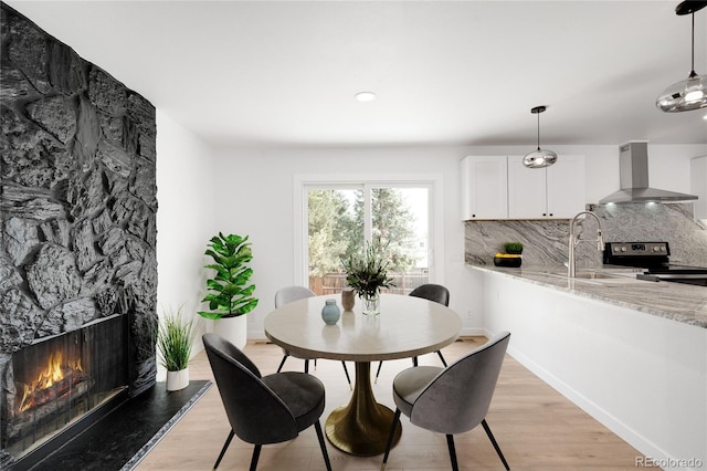 dining space featuring a fireplace, light wood-type flooring, and baseboards