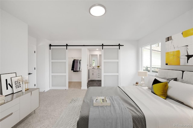 carpeted bedroom with baseboards, a closet, a walk in closet, and a barn door