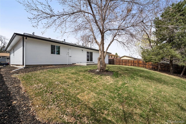 rear view of property featuring fence and a yard