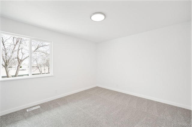 carpeted spare room featuring visible vents and baseboards