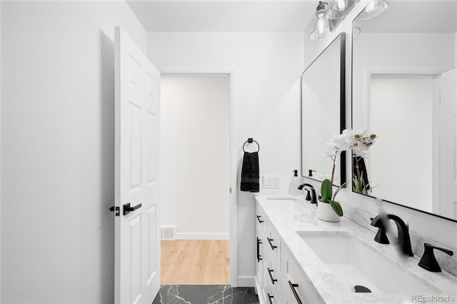 full bathroom with baseboards, a sink, and double vanity
