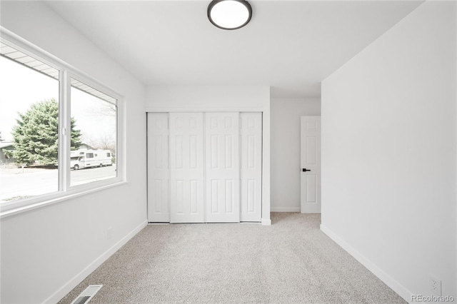 unfurnished bedroom featuring carpet floors, a closet, baseboards, and multiple windows