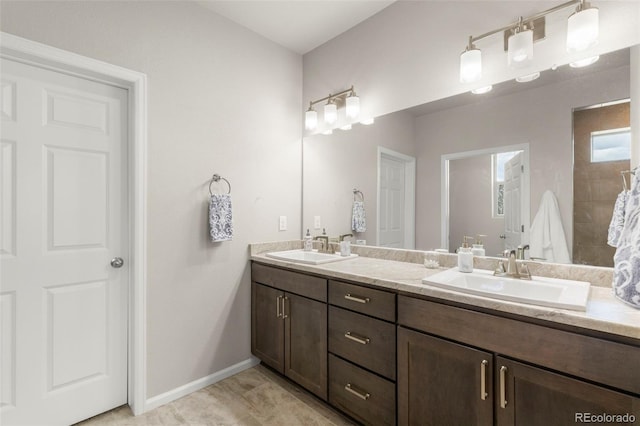 full bath featuring baseboards and double vanity