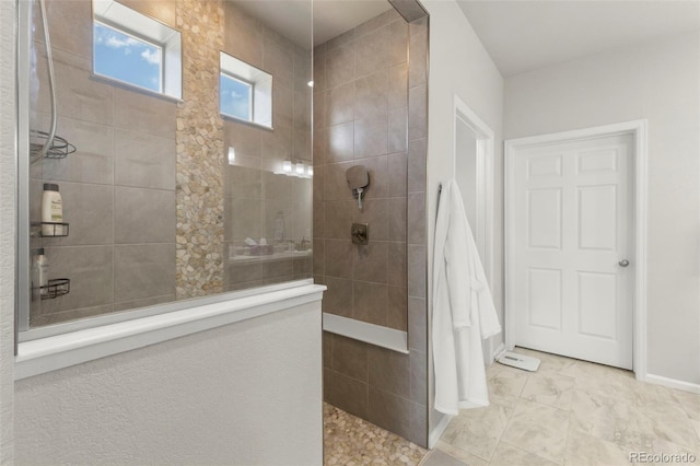 bathroom with a walk in shower, baseboards, and marble look tile flooring