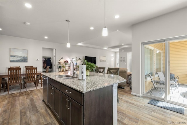 kitchen featuring a sink, open floor plan, light wood-style flooring, dark brown cabinetry, and recessed lighting