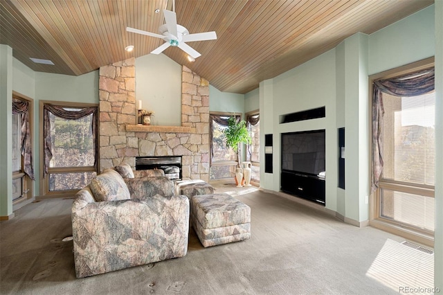 living room featuring a stone fireplace, ceiling fan, plenty of natural light, and wooden ceiling