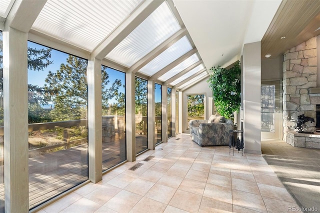 unfurnished sunroom featuring a stone fireplace and vaulted ceiling