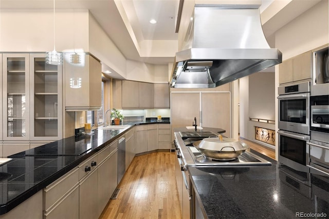 kitchen with sink, light hardwood / wood-style floors, decorative light fixtures, island range hood, and appliances with stainless steel finishes