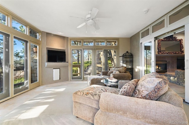 carpeted living room featuring a tile fireplace and ceiling fan