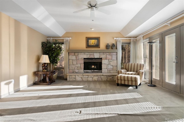 carpeted living room with a healthy amount of sunlight, a stone fireplace, ceiling fan, and lofted ceiling