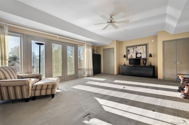 carpeted living room with ceiling fan and french doors