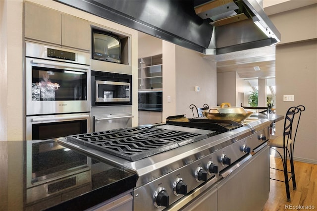 kitchen featuring light wood finished floors, baseboards, dark countertops, appliances with stainless steel finishes, and a warming drawer