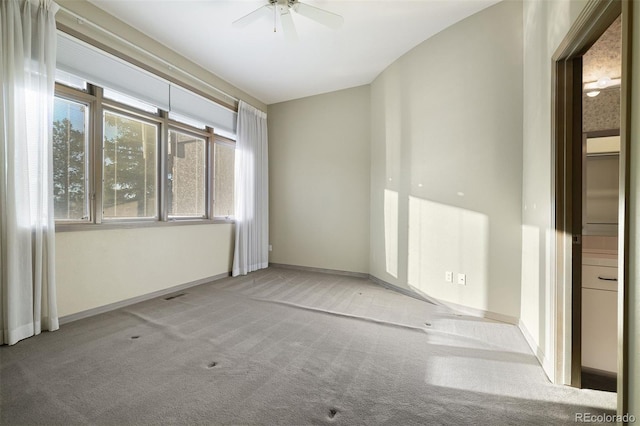 carpeted spare room featuring visible vents, baseboards, and ceiling fan