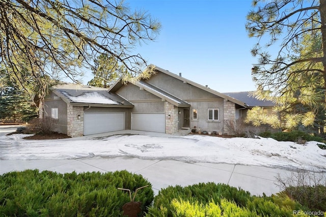 view of front of home with stone siding, an attached garage, and stucco siding