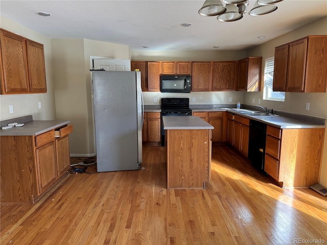 kitchen featuring sink, light hardwood / wood-style flooring, black appliances, and a kitchen island