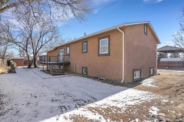 snow covered rear of property featuring a shed and a deck