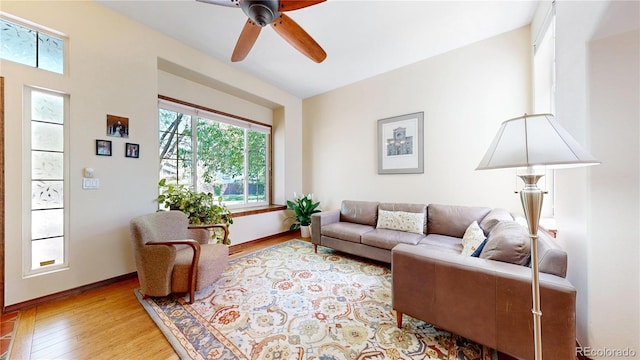 living area featuring wood finished floors, a ceiling fan, and baseboards
