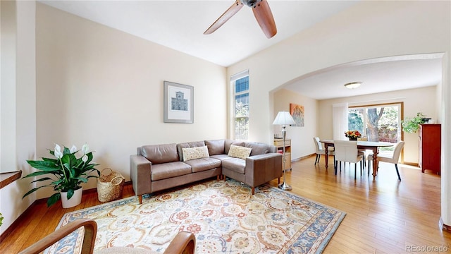 living area featuring ceiling fan, arched walkways, and light wood-style floors