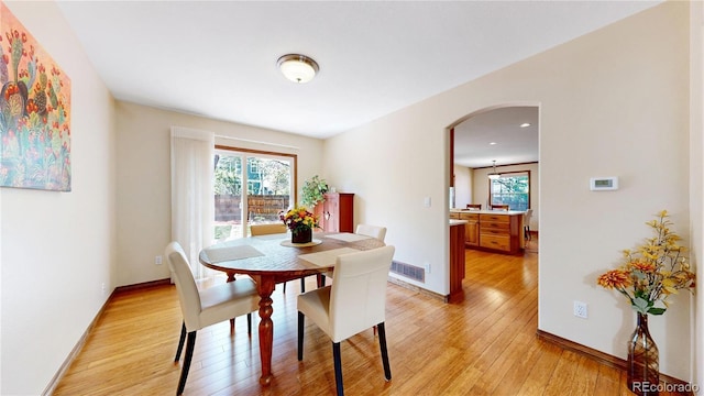 dining room featuring light wood-style floors, arched walkways, baseboards, and recessed lighting