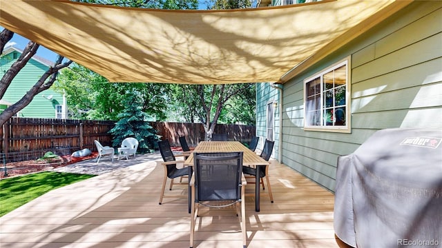 wooden terrace with outdoor dining space, a fenced backyard, and area for grilling