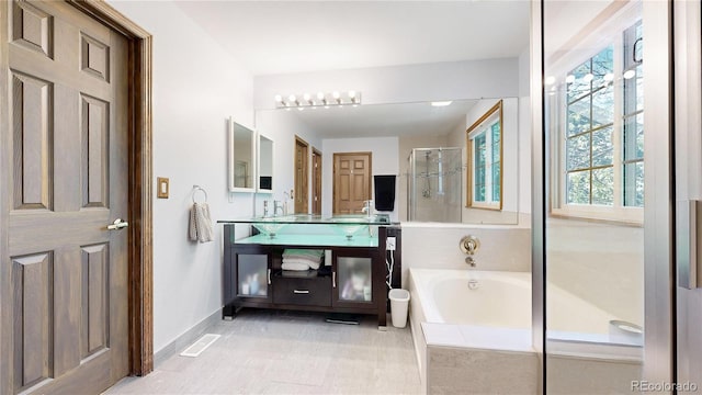 full bathroom with a shower stall, a garden tub, baseboards, and vanity