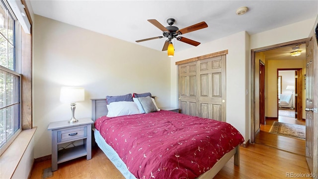 bedroom with wood finished floors, a closet, baseboards, and ceiling fan